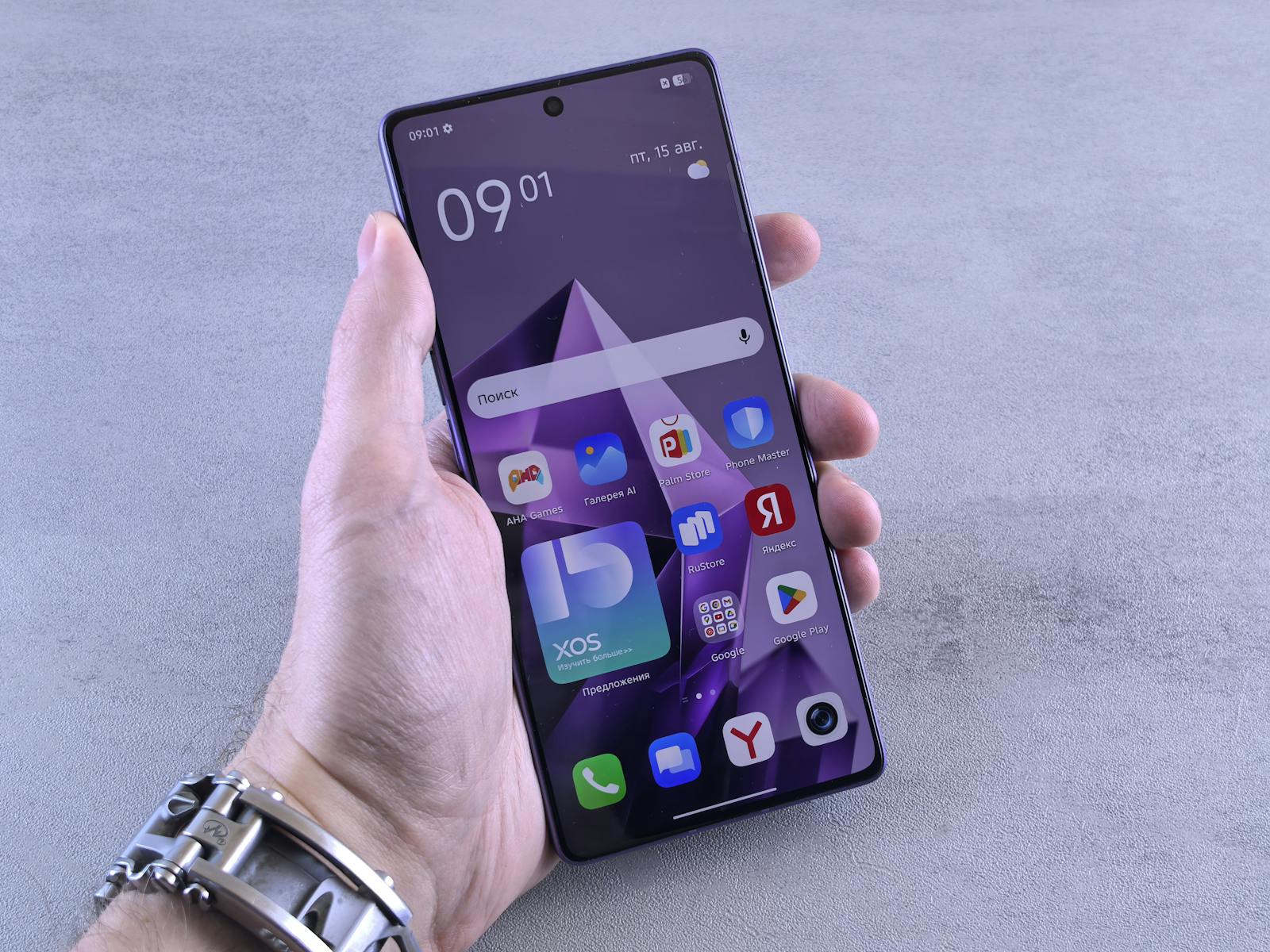 A hand holding a smartphone with various apps on the screen.